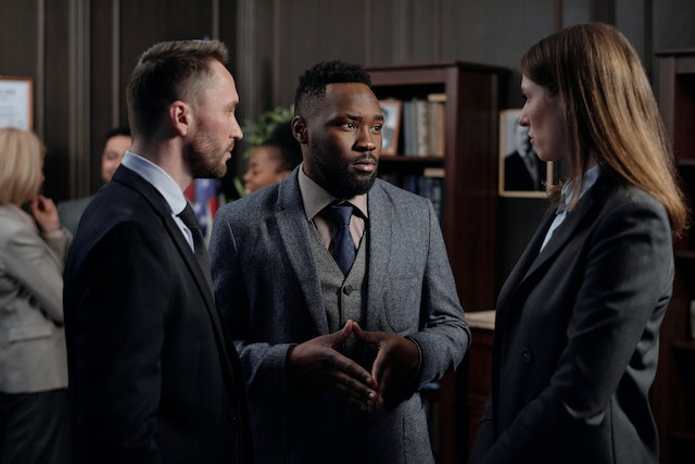 three lawyers in suits discussing in a room