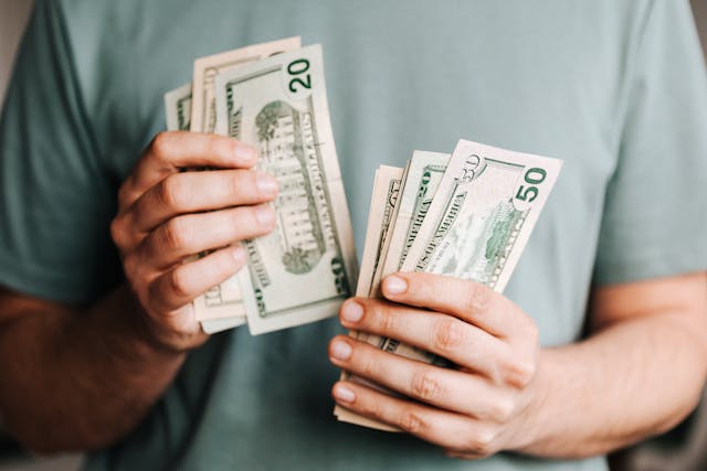 person in blue shirt counting bills